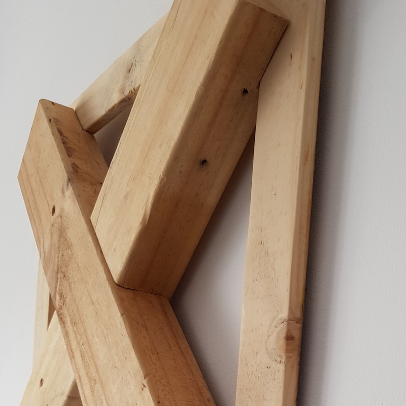 Houten wandversiering Woodout. Deze unieke prachtige houten 3D wandsculptuur is gemaakt van gerecyclede hout. De afgedankte balken zijn de eyecatcher van het geheel, mooi gedrapeerd over de planken welke eerder als vloer van een pallet dienden. Her en der is nog een in onmin geraakte spijker terug te vinden uit een voorgaand leven. Het geheel is samengebracht in een vurenhouten frame.

Op de balken zijn nog stukjes markering van hun voorgaande leven terug te vinden, wat een extra stukje authenticiteit toevoegt. De balken zijn bevestigd op een vloertje van oude palletplanken, welke nog de sporen in zich hebben van hun vorige bestaan. Spijkergaatjes en zelfs nog een aantal oude afgezaagde spijkers prijken als oude wachters in het gedroogde hout.

De compositie is afgemaakt met een vurenhouten rand, bijna om aan te geven dat het verleden daarbinnen dient te blijven. Het is een uniek kunstwerk, handgemaakt en er is er geen één gelijk. Het hout is tot rust gekomen, ondanks de sporen van een werkbaar leven. Een prachtige wanddecoratie om aan de muur te hangen.