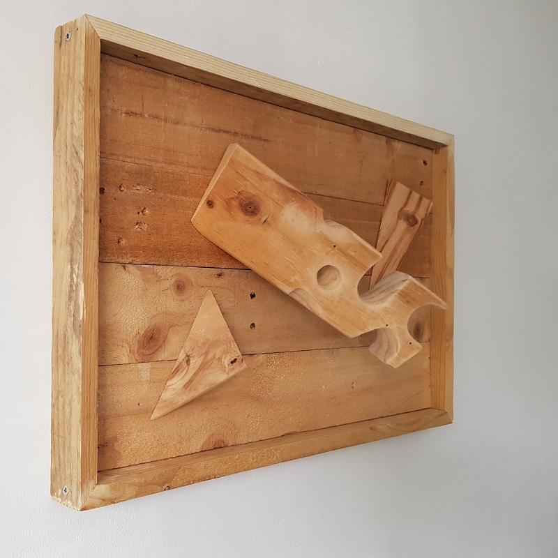 3D WallArt houten wandversiering Kaasplankje. Compositie van bewerkt afvalhout, van gebruikte pallet tot muurkunst. Dit houten 3D wandpaneel is volledig gemaskt van resthout (oude wegwerp pallets). De balk van de pallet is bewerkt zodat deze is vervormd tot een gatenkaasblok met daarbij twee diagonaal gezaagde hoeken. 

De planken van de pallet zijn gebruikt voor de bodem en lijst. Expres is er voor gekozen om de gebruikssporen uit het voorgaande leven als pallet terug te laten komen. Kleine beschadigingetjes, een schroef of spijkergat of bluts hoort daarbij. Dit zijn de littekens van het werkstuk. 

De afmetingen van het houten wandpaneel, ca. 40 x 60 cm maken dat het eenvoudig op meerdere plaatsen haar plek kan vinden. Ondanks het 3D effect met de uitstekende centrale balk komt het werkstuk niet meer dan 17 cm van de muur, zodat het ook in kleinere ruimtes als een kantoor of gang niet in de werkruimte uitsteekt.