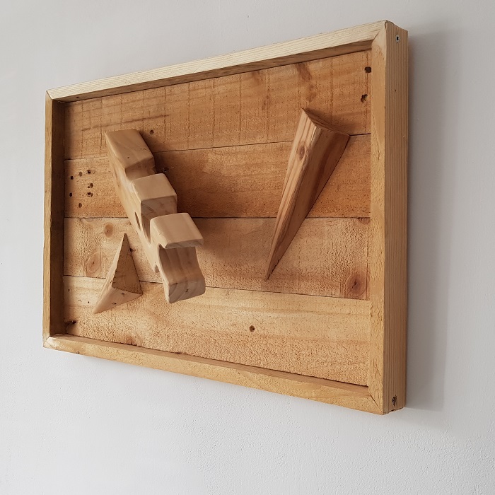 3D WallArt houten wandversiering Kaasplankje. Compositie van bewerkt afvalhout, van gebruikte pallet tot muurkunst. Dit houten 3D wandpaneel is volledig gemaskt van resthout (oude wegwerp pallets). De balk van de pallet is bewerkt zodat deze is vervormd tot een gatenkaasblok met daarbij twee diagonaal gezaagde hoeken. 

De planken van de pallet zijn gebruikt voor de bodem en lijst. Expres is er voor gekozen om de gebruikssporen uit het voorgaande leven als pallet terug te laten komen. Kleine beschadigingetjes, een schroef of spijkergat of bluts hoort daarbij. Dit zijn de littekens van het werkstuk. 

De afmetingen van het houten wandpaneel, ca. 40 x 60 cm maken dat het eenvoudig op meerdere plaatsen haar plek kan vinden. Ondanks het 3D effect met de uitstekende centrale balk komt het werkstuk niet meer dan 17 cm van de muur, zodat het ook in kleinere ruimtes als een kantoor of gang niet in de werkruimte uitsteekt.