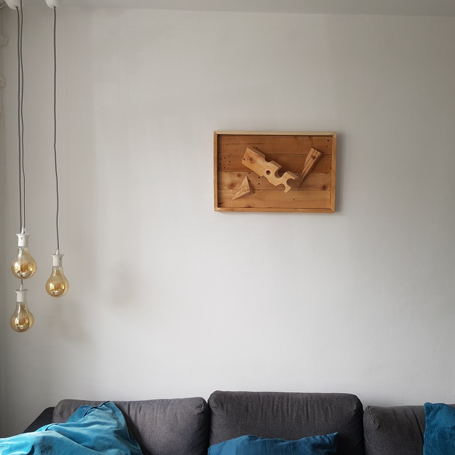 3D WallArt houten wandversiering Kaasplankje. Compositie van bewerkt afvalhout, van gebruikte pallet tot muurkunst. Dit houten 3D wandpaneel is volledig gemaskt van resthout (oude wegwerp pallets). De balk van de pallet is bewerkt zodat deze is vervormd tot een gatenkaasblok met daarbij twee diagonaal gezaagde hoeken. 

De planken van de pallet zijn gebruikt voor de bodem en lijst. Expres is er voor gekozen om de gebruikssporen uit het voorgaande leven als pallet terug te laten komen. Kleine beschadigingetjes, een schroef of spijkergat of bluts hoort daarbij. Dit zijn de littekens van het werkstuk. 

De afmetingen van het houten wandpaneel, ca. 40 x 60 cm maken dat het eenvoudig op meerdere plaatsen haar plek kan vinden. Ondanks het 3D effect met de uitstekende centrale balk komt het werkstuk niet meer dan 17 cm van de muur, zodat het ook in kleinere ruimtes als een kantoor of gang niet in de werkruimte uitsteekt.