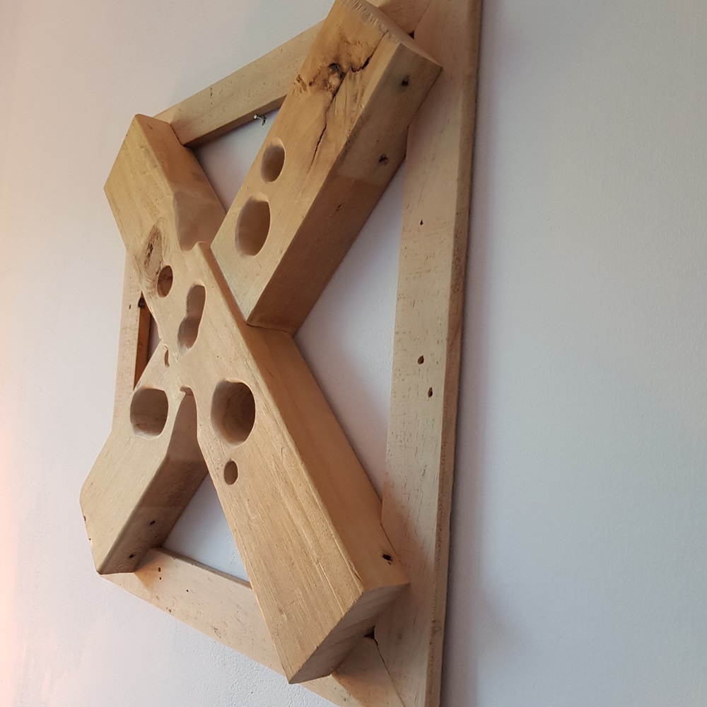 Houten wandversiering Woodout. Deze unieke prachtige houten 3D wandsculptuur is gemaakt van gerecyclede hout. De afgedankte balken zijn de eyecatcher van het geheel, mooi gedrapeerd over de planken welke eerder als vloer van een pallet dienden. Her en der is nog een in onmin geraakte spijker terug te vinden uit een voorgaand leven. Het geheel is samengebracht in een vurenhouten frame.

Op de balken zijn nog stukjes markering van hun voorgaande leven terug te vinden, wat een extra stukje authenticiteit toevoegt. De balken zijn bevestigd op een vloertje van oude palletplanken, welke nog de sporen in zich hebben van hun vorige bestaan. Spijkergaatjes en zelfs nog een aantal oude afgezaagde spijkers prijken als oude wachters in het gedroogde hout.

De compositie is afgemaakt met een vurenhouten rand, bijna om aan te geven dat het verleden daarbinnen dient te blijven. Het is een uniek kunstwerk, handgemaakt en er is er geen één gelijk. Het hout is tot rust gekomen, ondanks de sporen van een werkbaar leven. Een prachtige wanddecoratie om aan de muur te hangen.